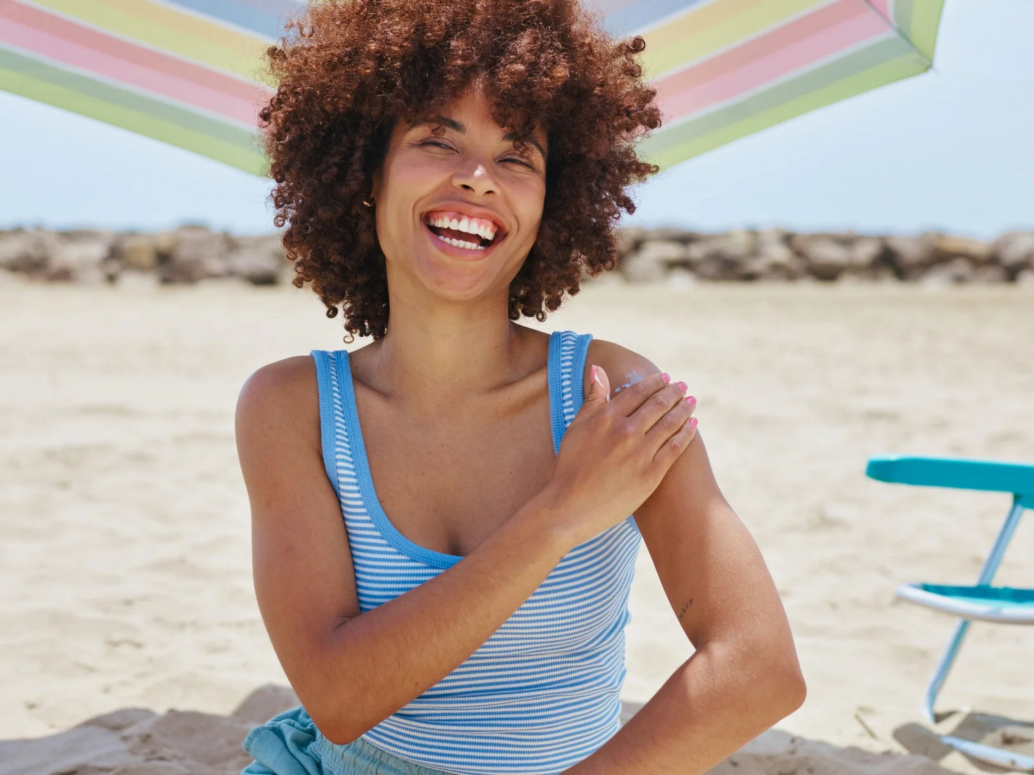 A smiling woman applying on sunscreen on her shoulder