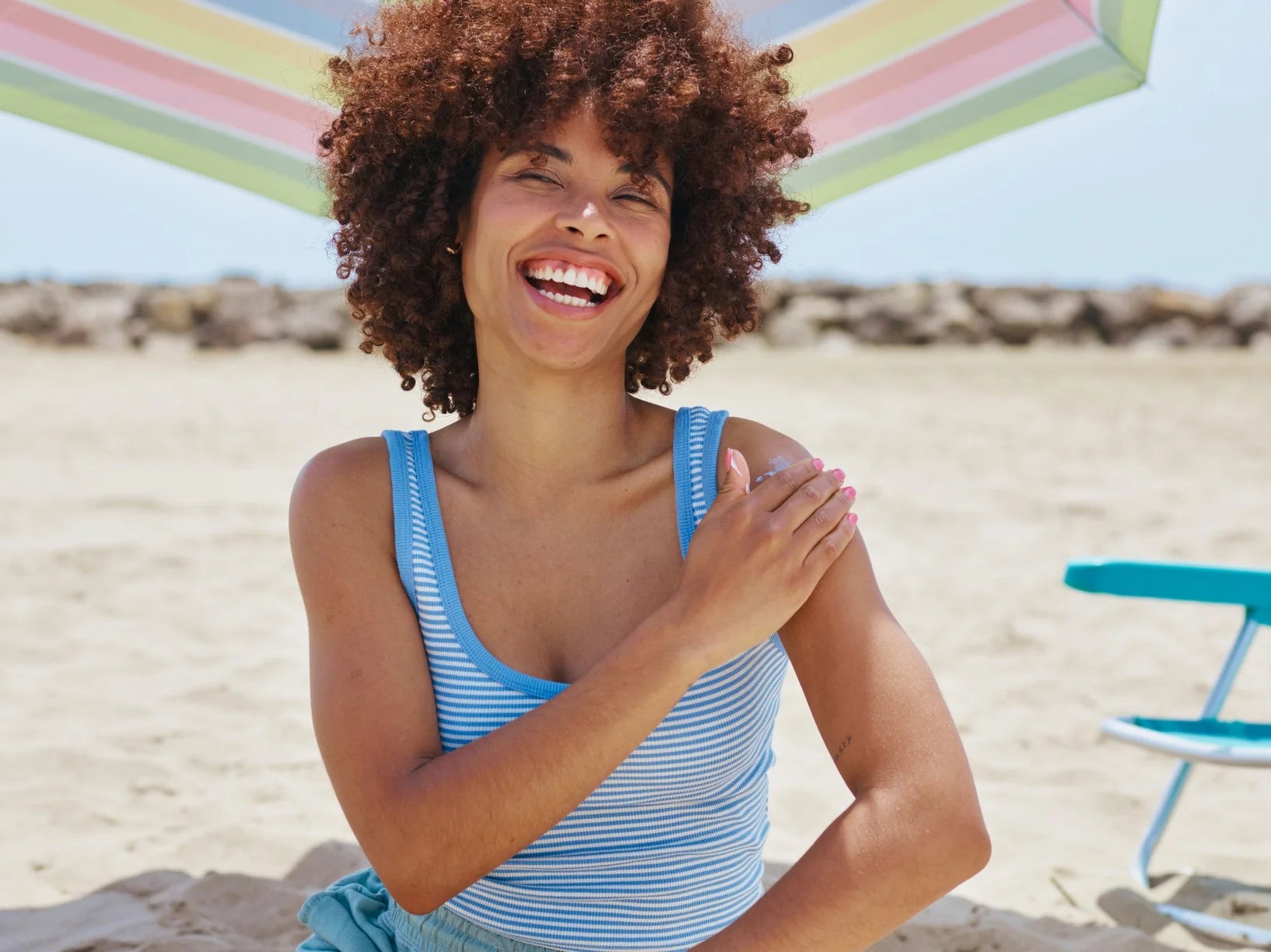 A smiling woman applying on sunscreen on her shoulder
