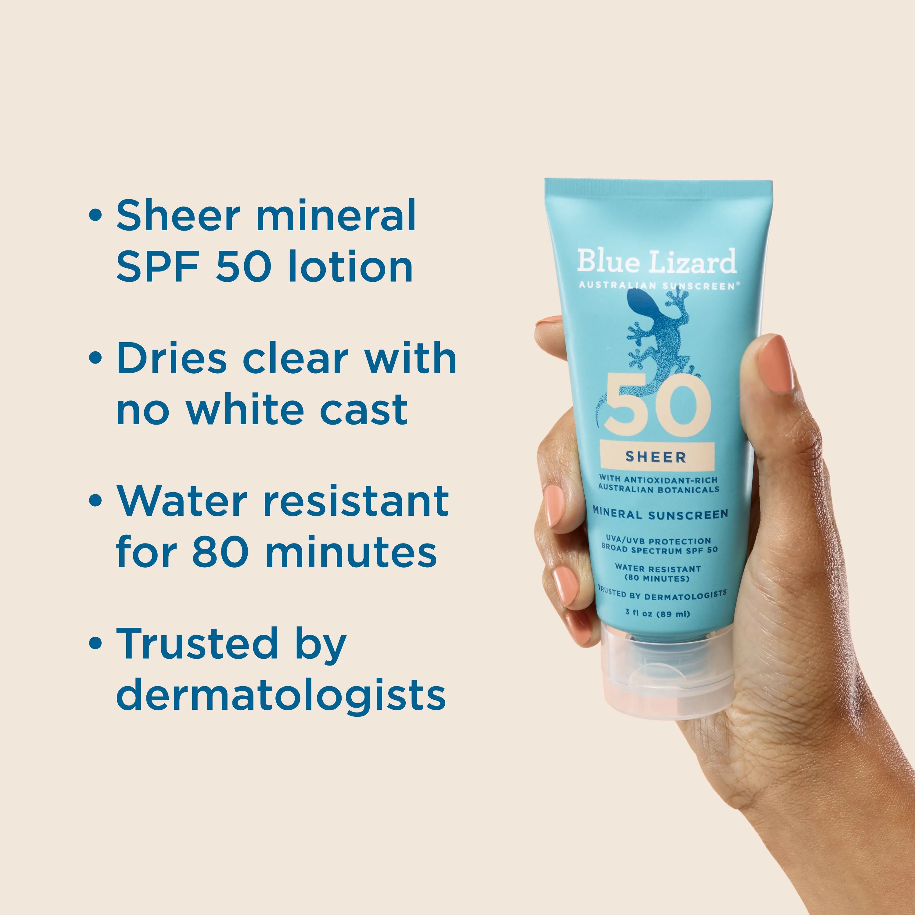 Hand holding a Blue Lizard Sheer SPF 50 mineral sunscreen tube with product features listed on an beige background