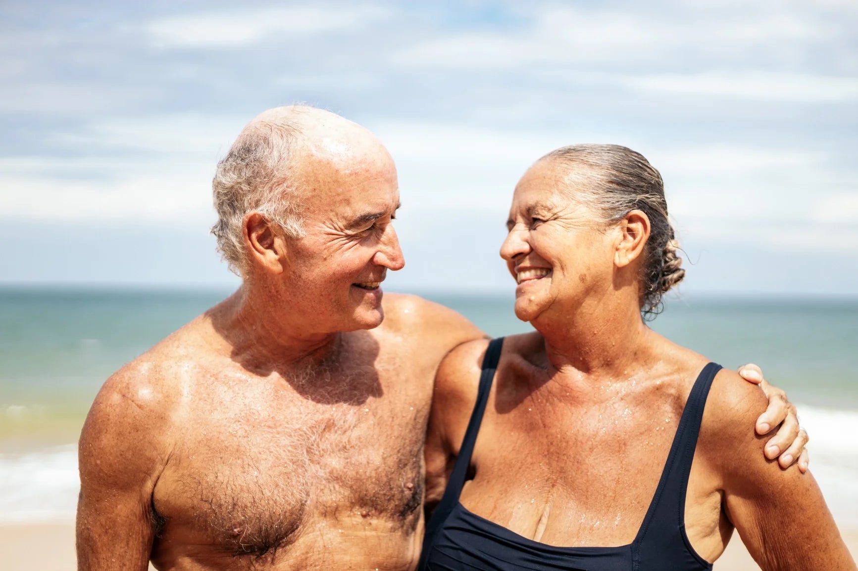 Senior couple smiling at each other on the beach.