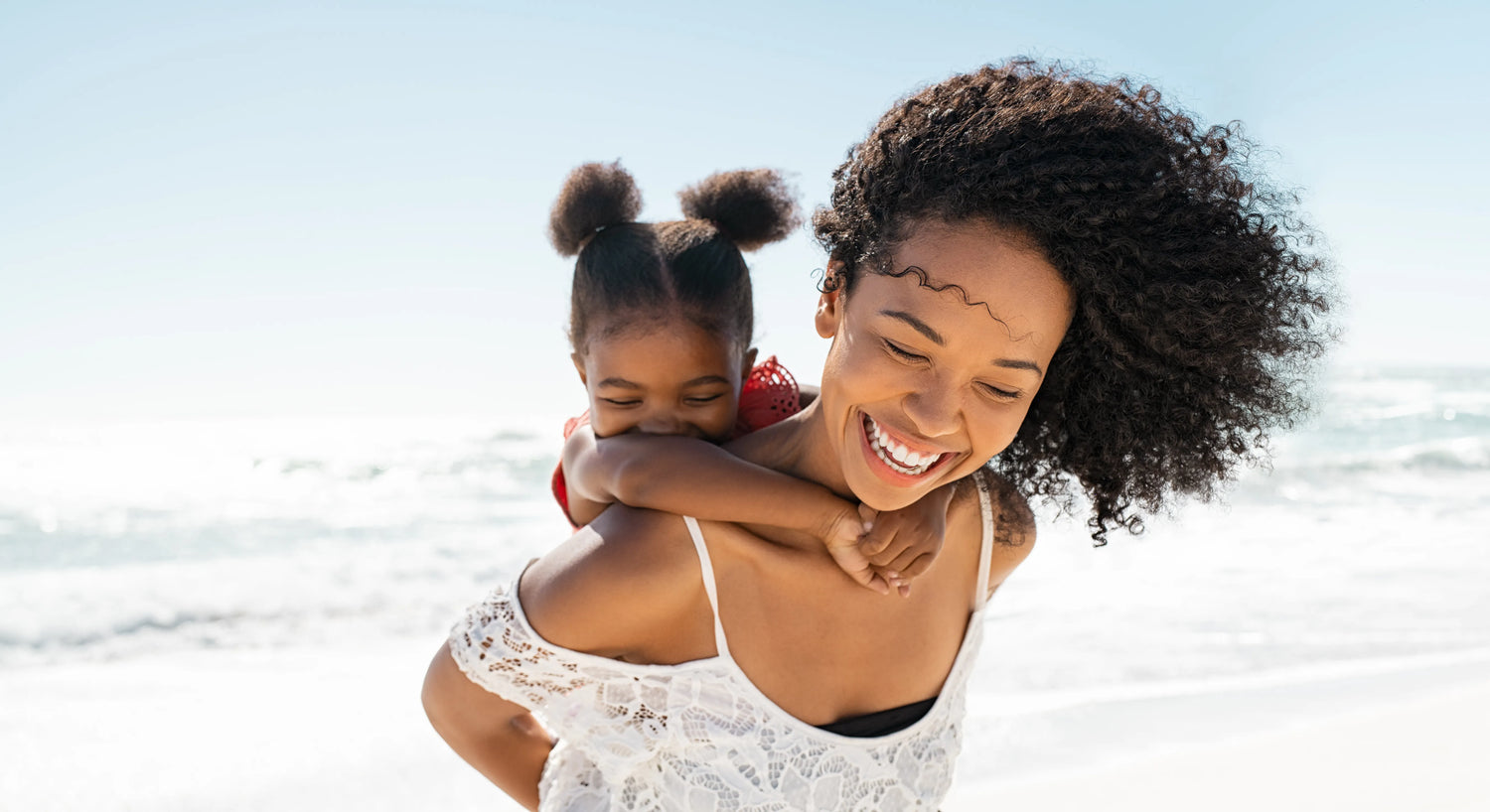 A woman at the beach with a child on her back