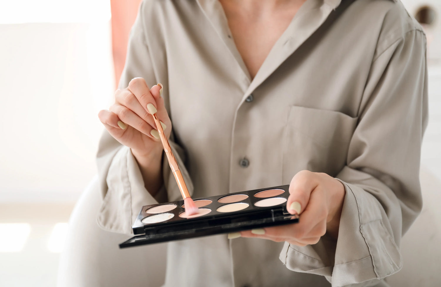 Person using a makeup brush with a palette