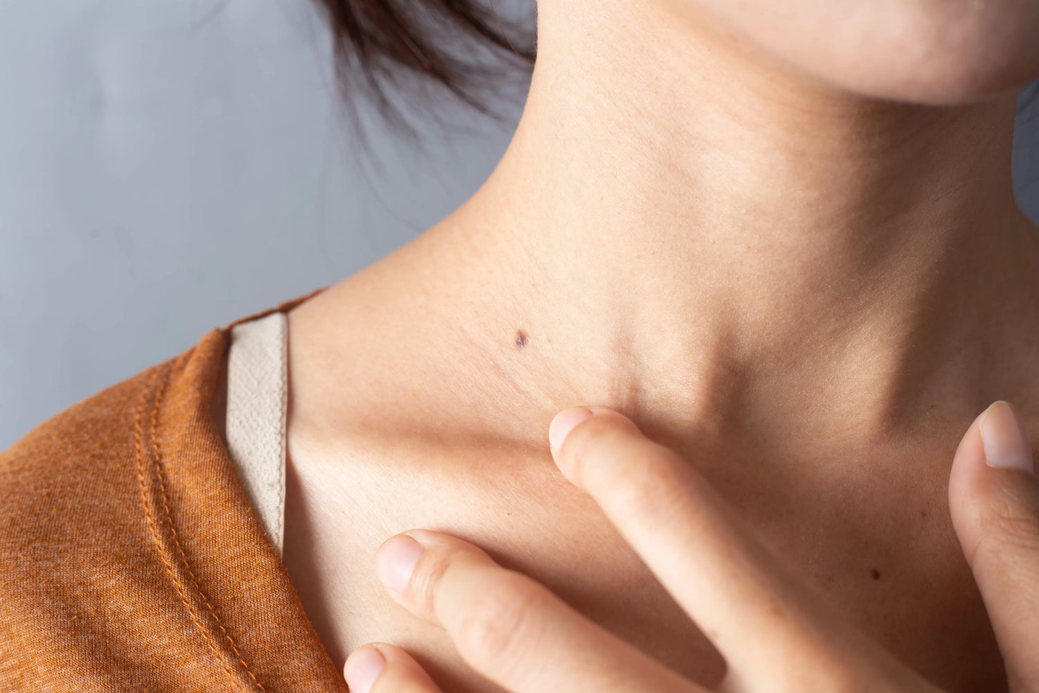 Person examining a mole on their neck