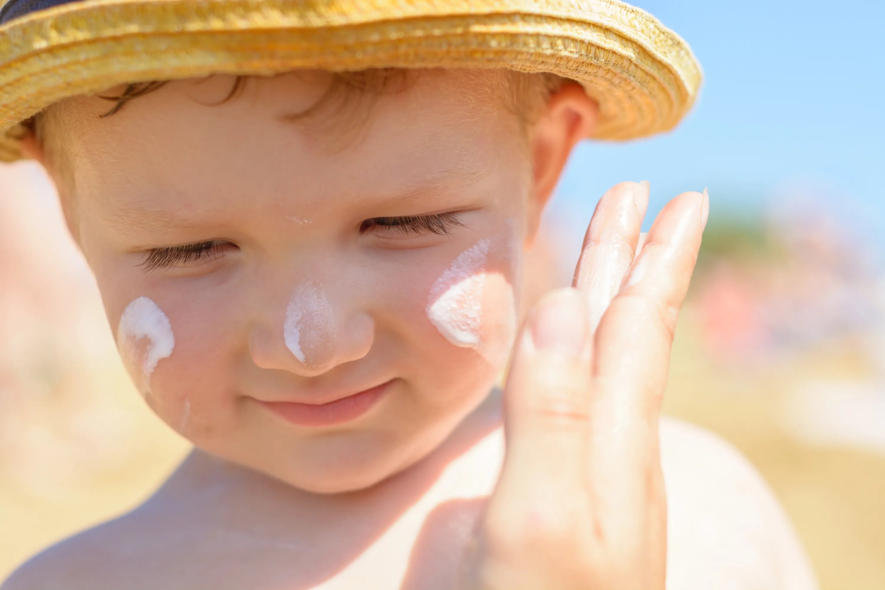 A child in a hat with sunscreen on his face