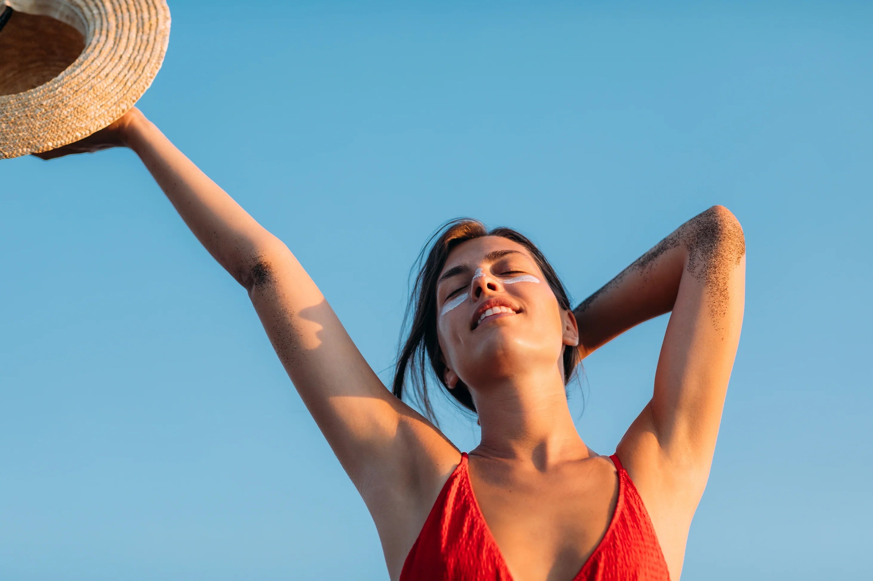 A woman in a red swimming suit holding a straw hat