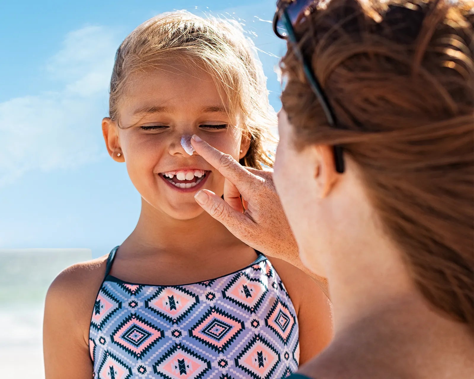 A woman applying Blue Lizard sunscreen on a child's nose