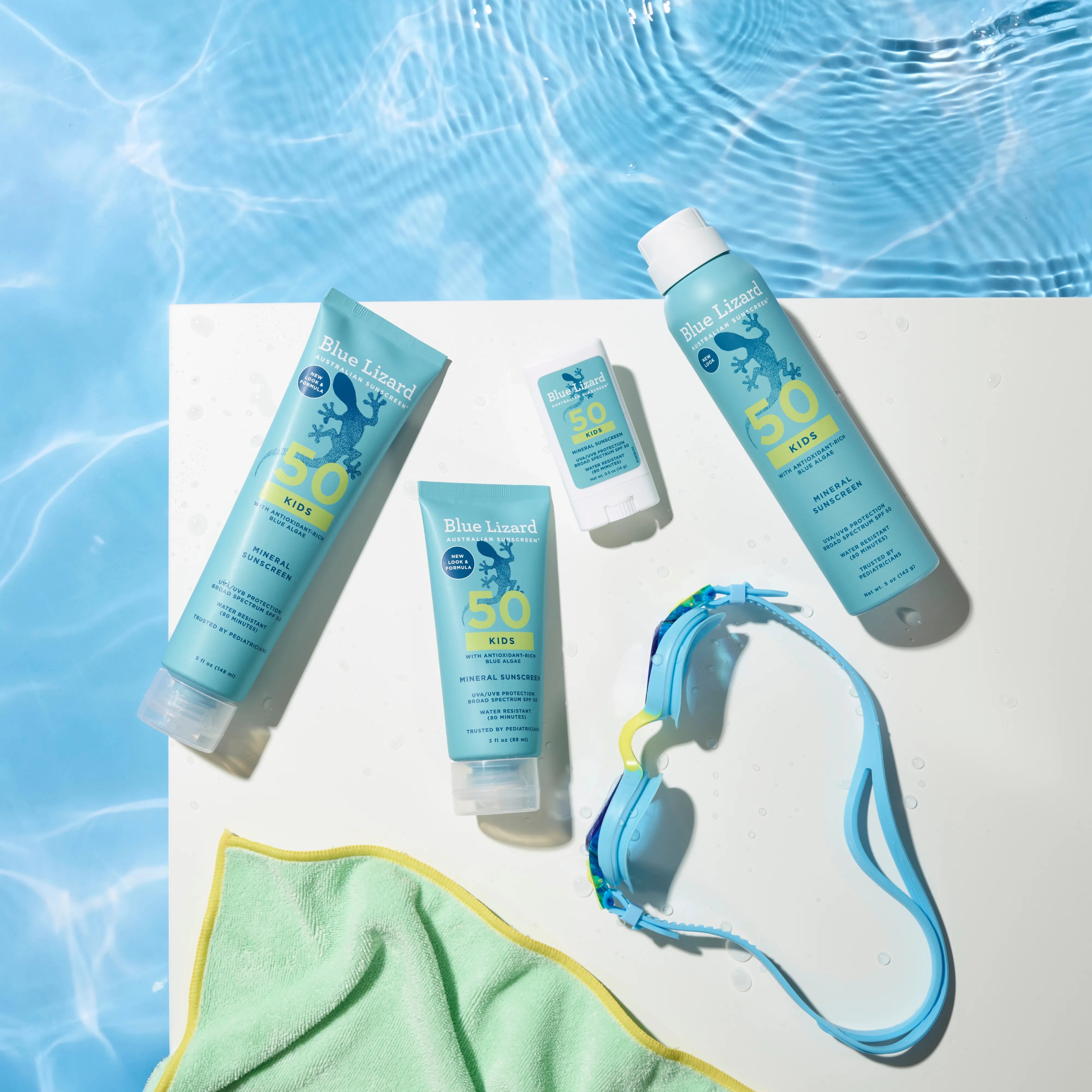 Blue Lizard mineral sunscreen SPF 50 kids collection with a towel and goggles next to a swimming pool