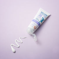 Sensitive Face Mineral Sunscreen with smear of product on purple background